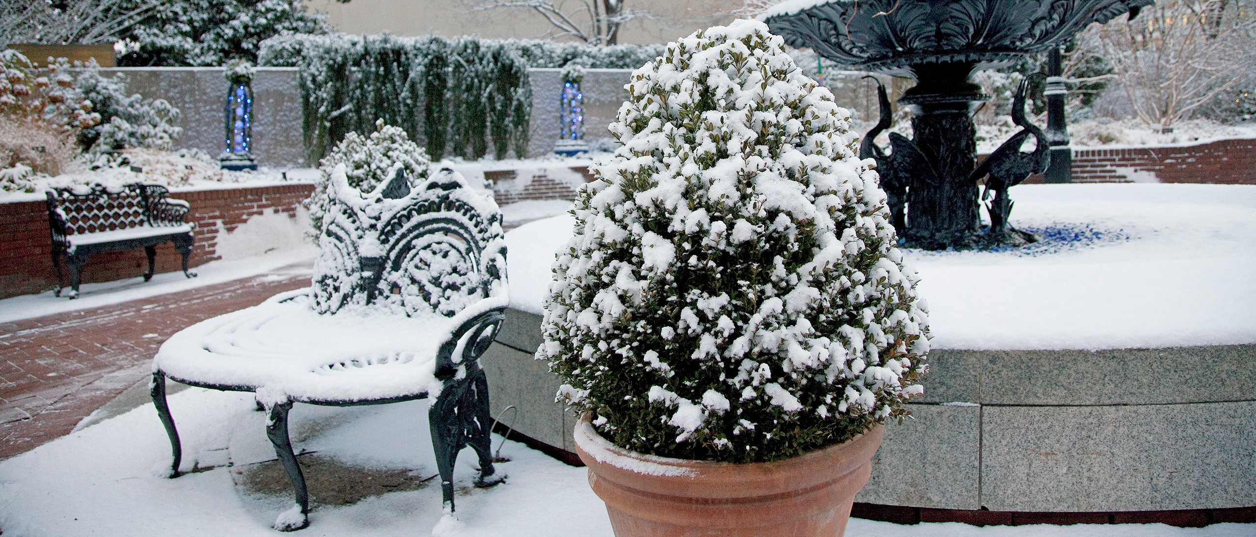 Cast iron three-tiered fountain and benches covered in snow