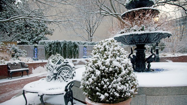 Cast iron three-tiered fountain and benches covered in snow