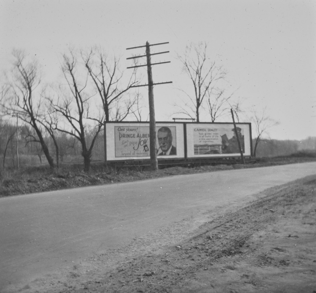 Billboards by the roadside advertising Prince Albert tobacco and Camel cigarettes.