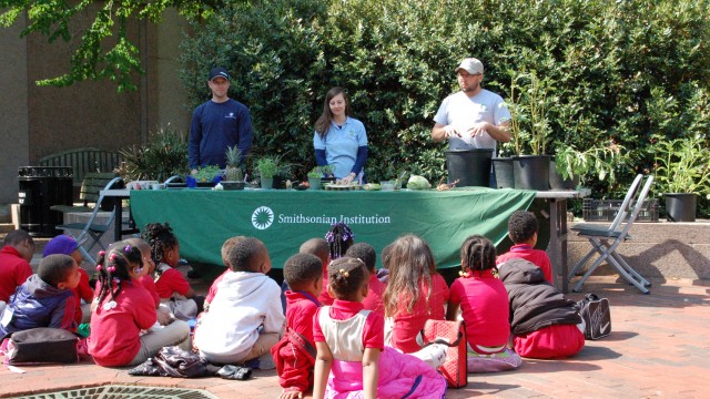 Children sitting on walkway watching plant demonstration