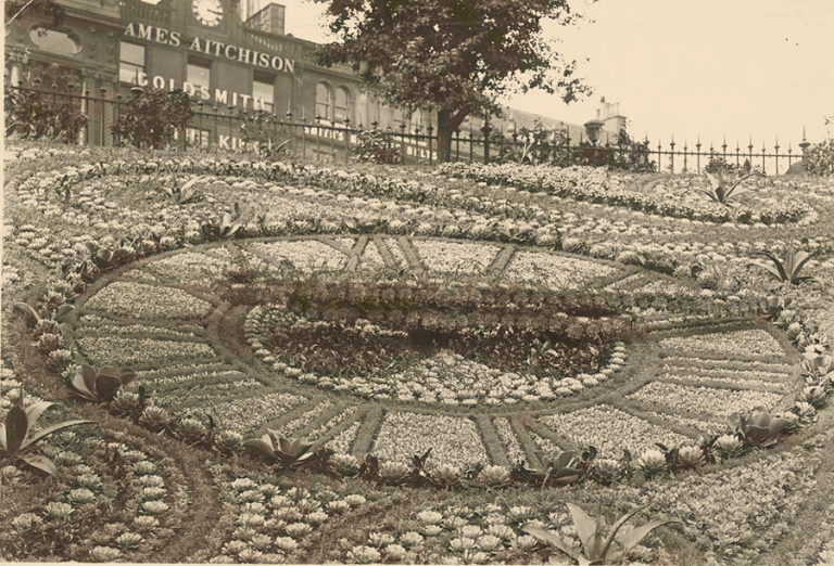 Vintage image of large clock created through flower plantings on the side of a hill