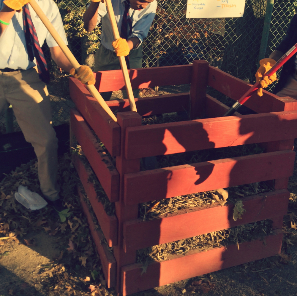 People digging in red wooden compost bin