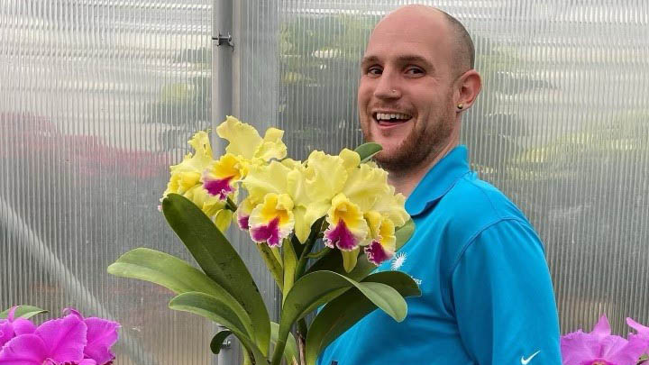 Justin Kondrat, horticulturist with orchid in the Smithsonian Gardens Orchid Collection.