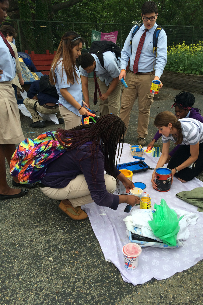 Students in school uniforms arranging paint containers on a dropcloth