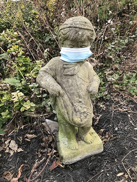 Sculpture of child in "My Church Garden" wearing mask during the COVID-19 pandemic.