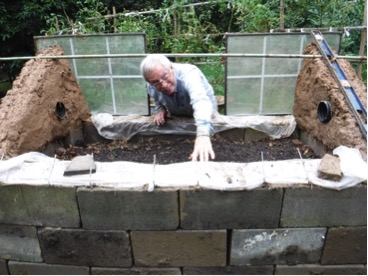 The cold frame is built of cbb, cement blocks, a glass cover, and other materials., Ed at work on the handicap-accessible cold frame.