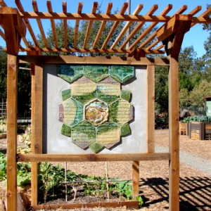 The Lafayette Community Garden peace pole, surrounded by a raised bed of flowers.