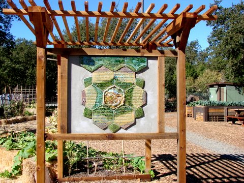 The Lafayette Community Garden peace pole, surrounded by a raised bed of flowers.