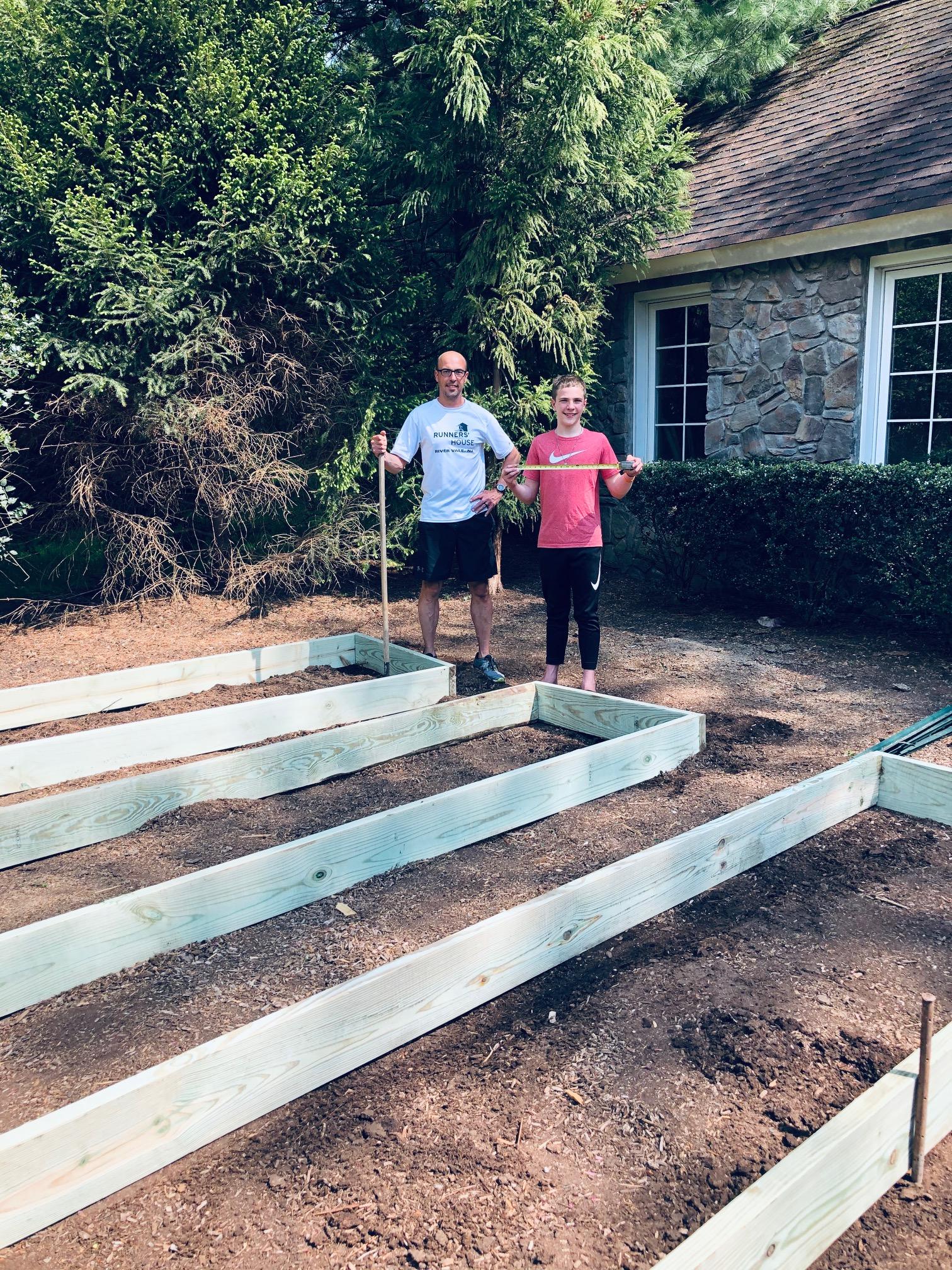 Ivan and his dad pose by the raised bed frames at Ivan's Garden.