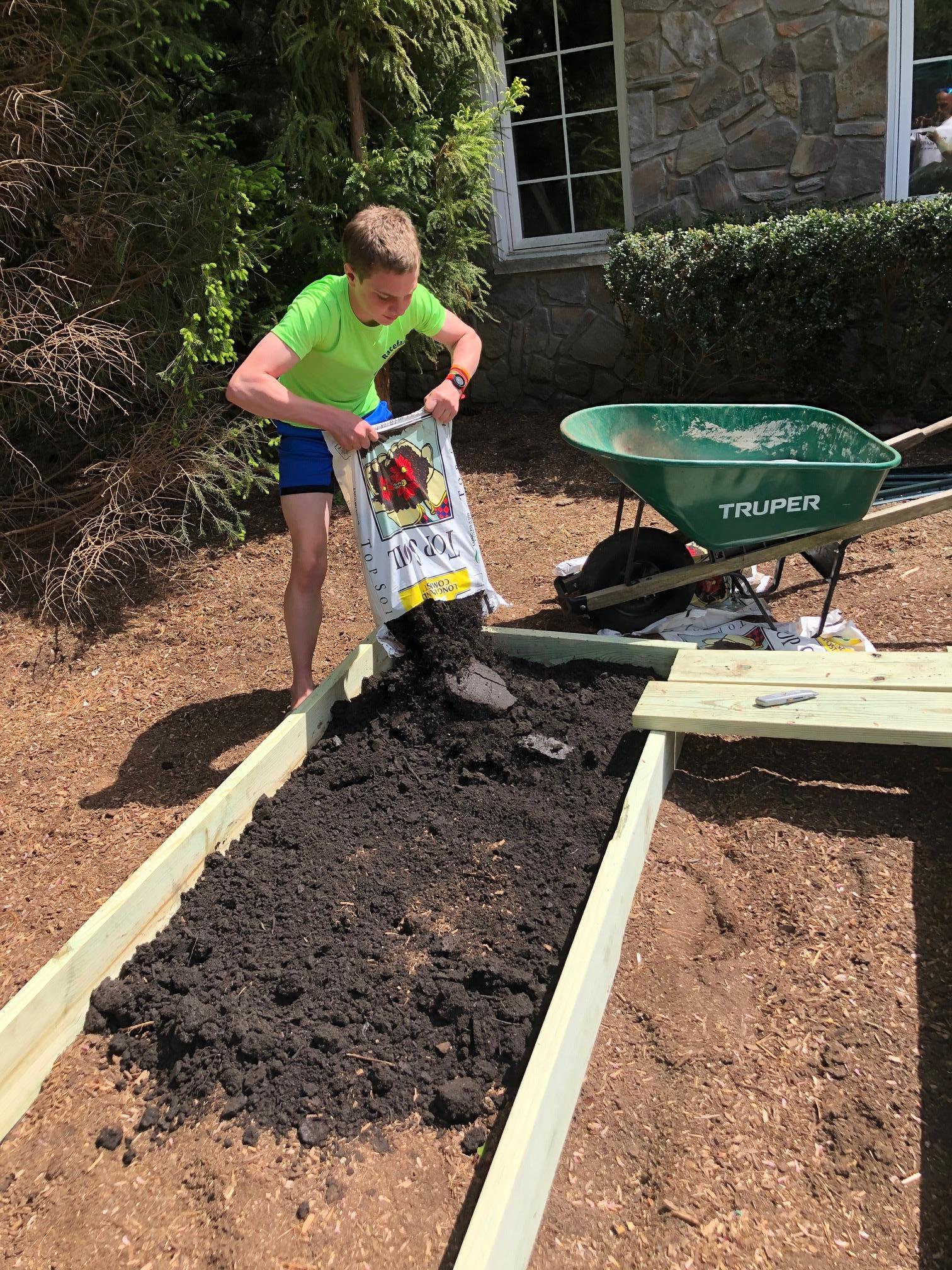 Ivan fills his garden beds with soil at Ivan's Garden.